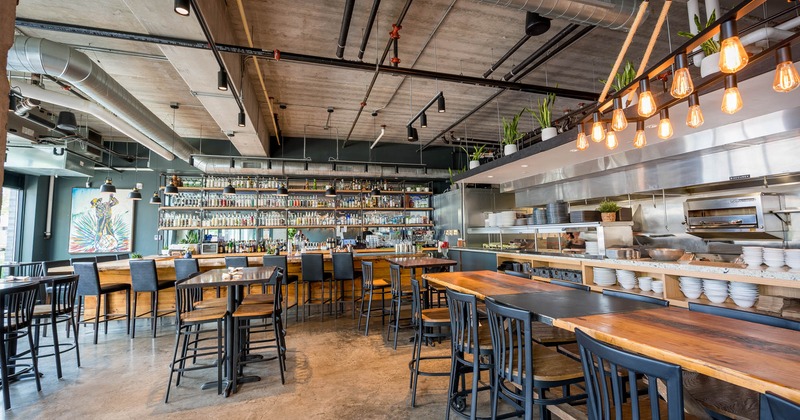 Interior, tables and chairs lined up, bar and bar stools in the back