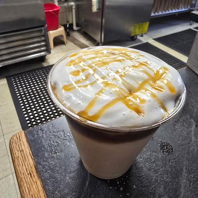 An iced Caramel Macchiato topped with Cold Foam and drizzled with caramel sitting on a counter.