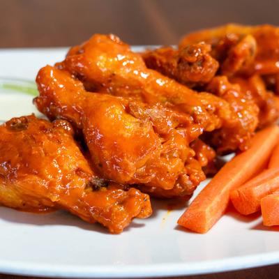 Buffalo wings and carrots, close up.