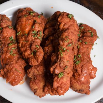Boneless buffalo wings garnished with fresh herbs.