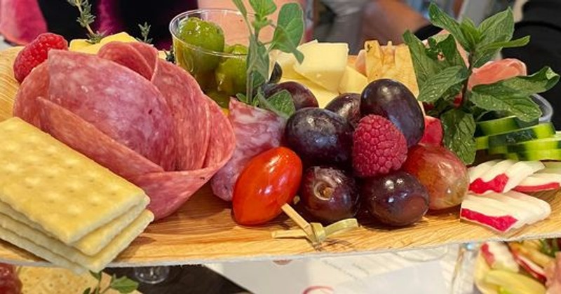 Charcuterie and cheese board with fresh fruits and crackers, close up