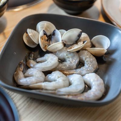 Raw shrimp and clams in a bowl, closeup.