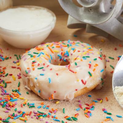 Donut with creamy white icing and colorful sprinkles.