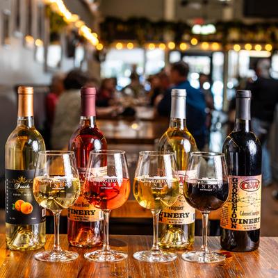 Four bottles of wine on a wooden table, each paired with a filled wine glass.