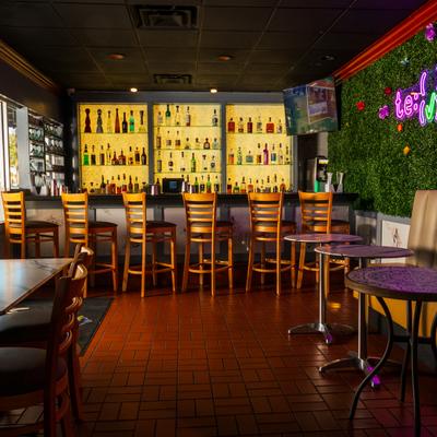 Bar area, tables, bar, drink rack behind.