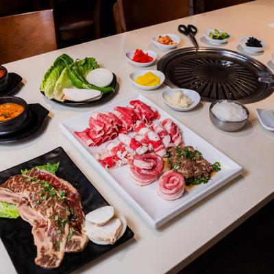Korean barbecue table with meats and side dishes.
