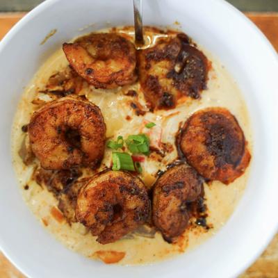 Blackened shrimp served over grits with sausage, peppers, and onions.