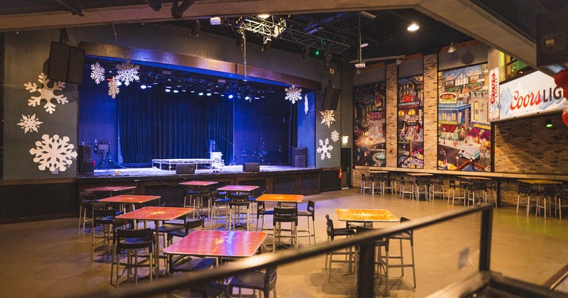 Interior, concert hall, large stage, speakers on the stage, tables and chairs