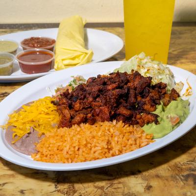 Seasoned meat, rice, beans with cheese, guacamole, salsas, tortillas, and a yellow drink.