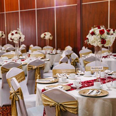 A banquet room adorned in white and gold decor for a wedding.