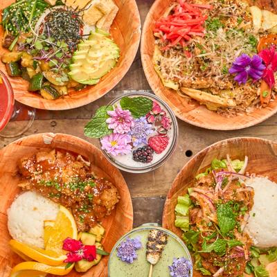 Colorful dishes and drinks garnished with flowers on a table.