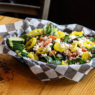 Spinach salad with feta, cucumbers, diced tomato, black olives, onions, and banana peppers.