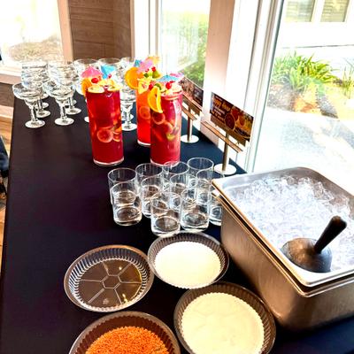 A table set with colorful cocktails, glassware, and ice.