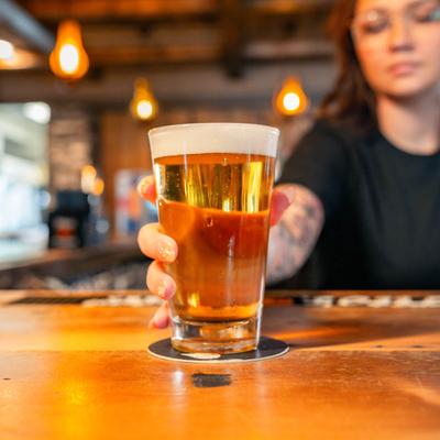 A bartender serves a glass of beer on bar counter.
