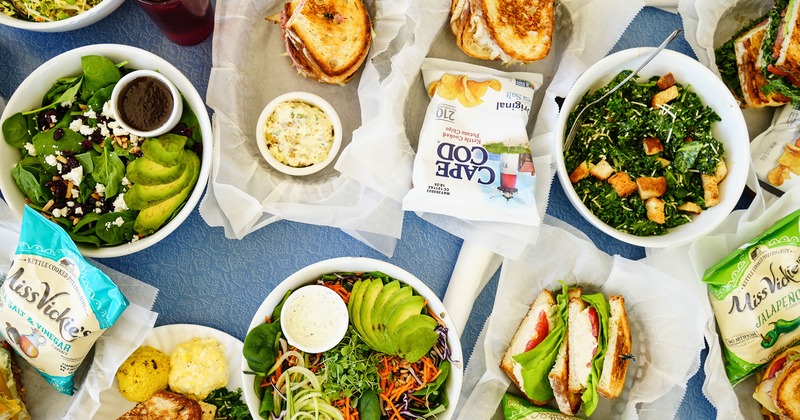 Assorted sandwiches and salads served on a table with bags of chips