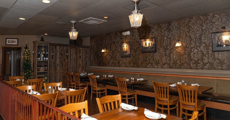 Restaurant dining area with wooden tables and chairs, warm lighting, and decorative wallpaper