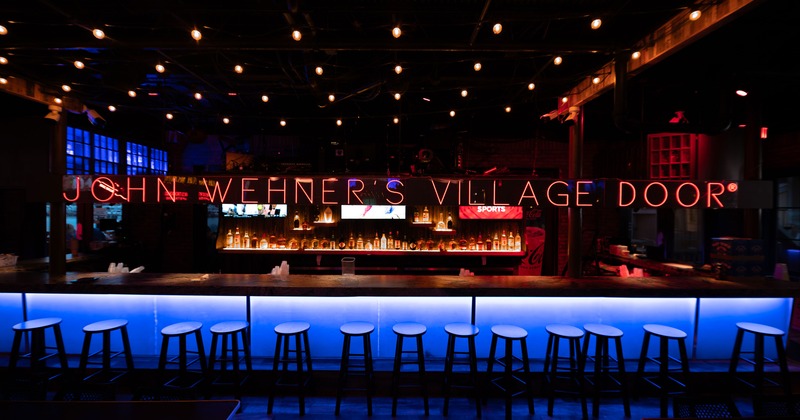 Bar counter illuminated by blue lights, featuring signage and a back bar stocked with bottles