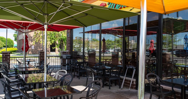 Exterior, partially covered seating area, restaurant front, tables under parasols