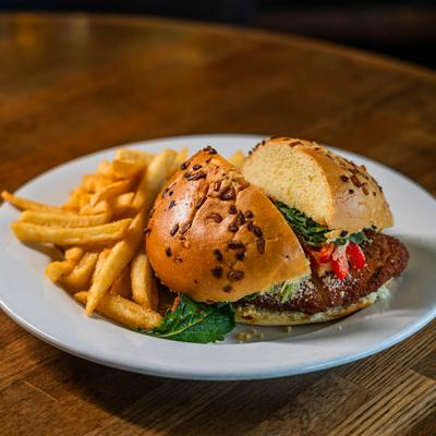 Red snapper sandwich and fries on a white plate.