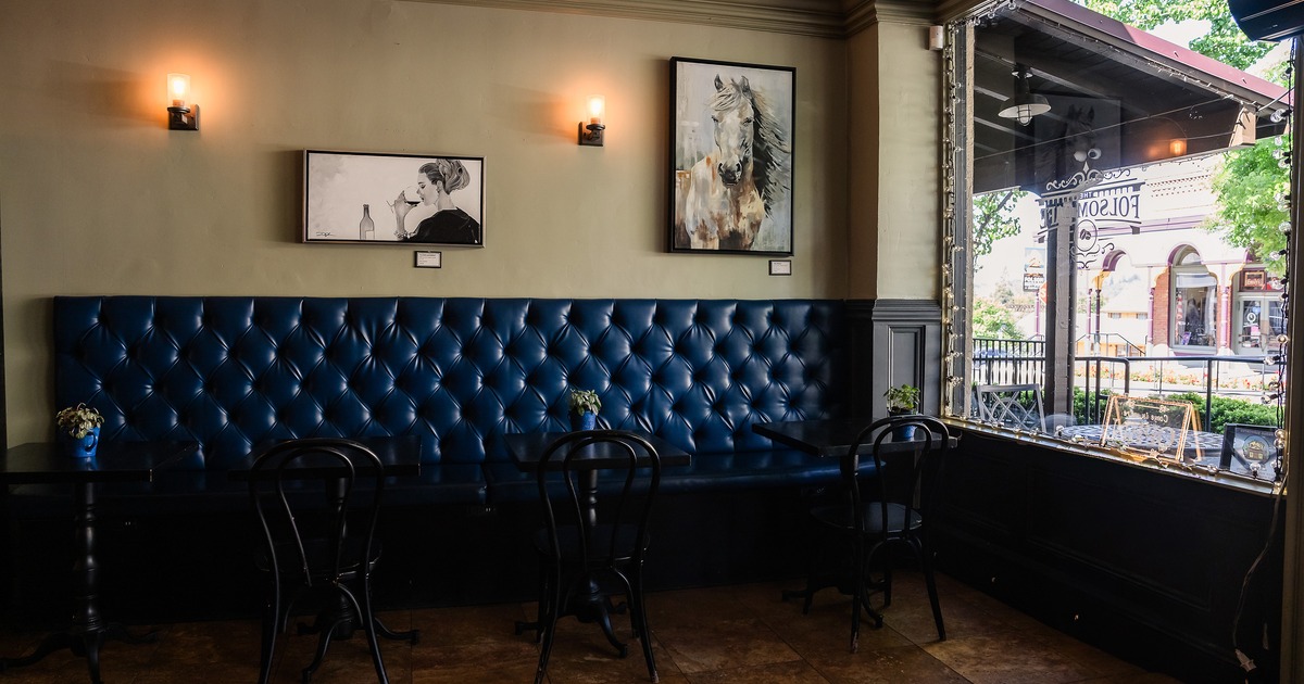 Rustic and casual interior space, lined up tables and chairs, and upholstered seats along the wall