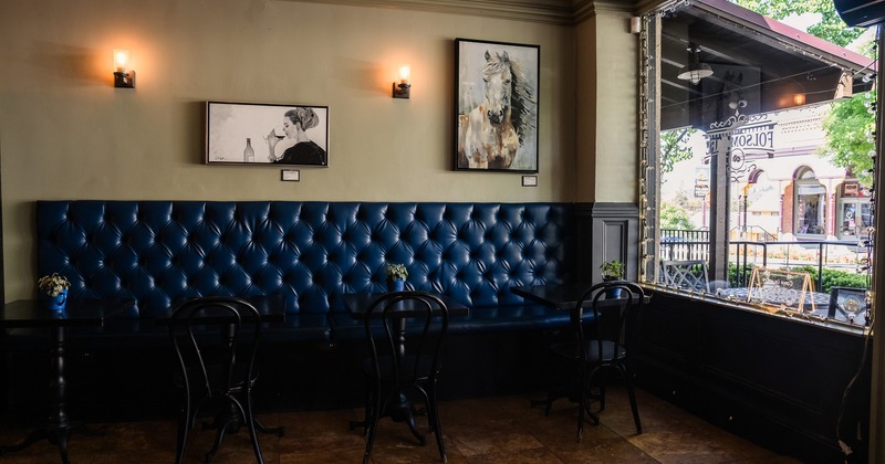 Rustic and casual interior space, lined up tables and chairs, and upholstered seats along the wall