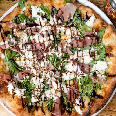 Proscuitto pizza with burrata cheese, arugula and a balsamic glaze drizzle.