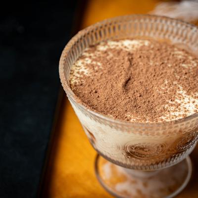 Tiramisu in a decorative glass, topped with a dusting of cocoa powder.