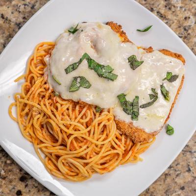 Chicken parmesan served over spaghetti.