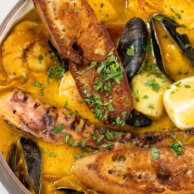 See food dish with fish, octopus, mussels, shrimp, scallops and toasted sourdough.