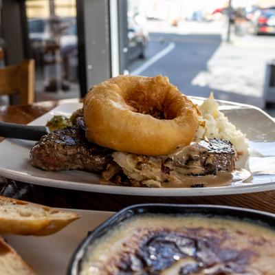New York steak with mashed potatoes, horseradish butter, and a colossal onion ring.