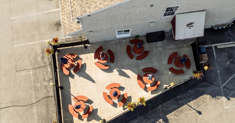 Aerial view of an outdoor seating area with circular red benches and tables next to a building