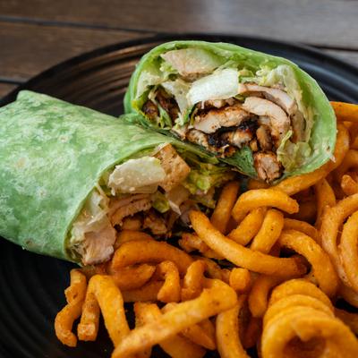 Chicken Caesar wrap served with curly fries.