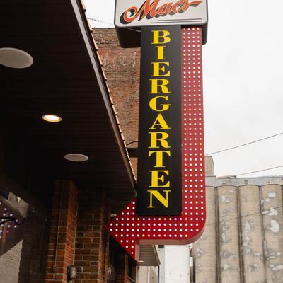 Exterior, sign reading Mac's Biergarten hangs on a brick building.