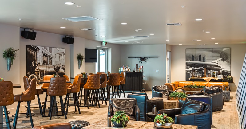 An upscale bowling lounge bar featuring tufted leather seating and aviation artwork