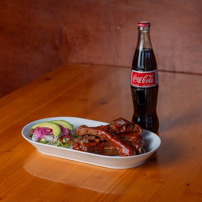 Baked pork ribs and a bottle of coke.