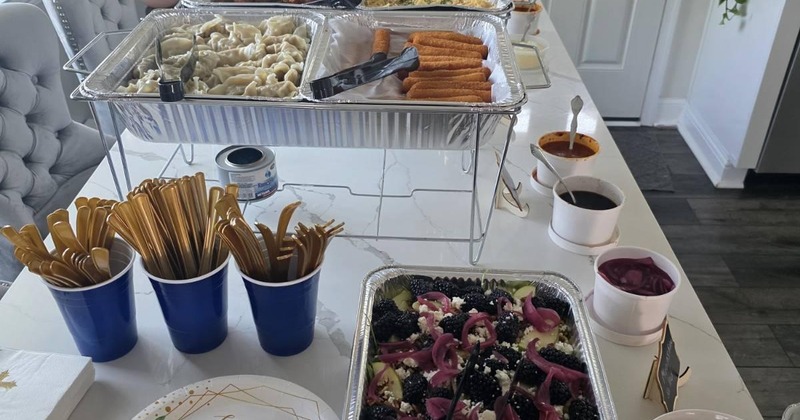 Catering table set up at a home with paper plates and eating utensils