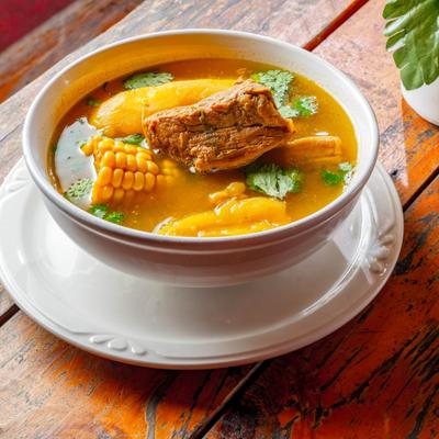 A bowl of soup with meat and corn.