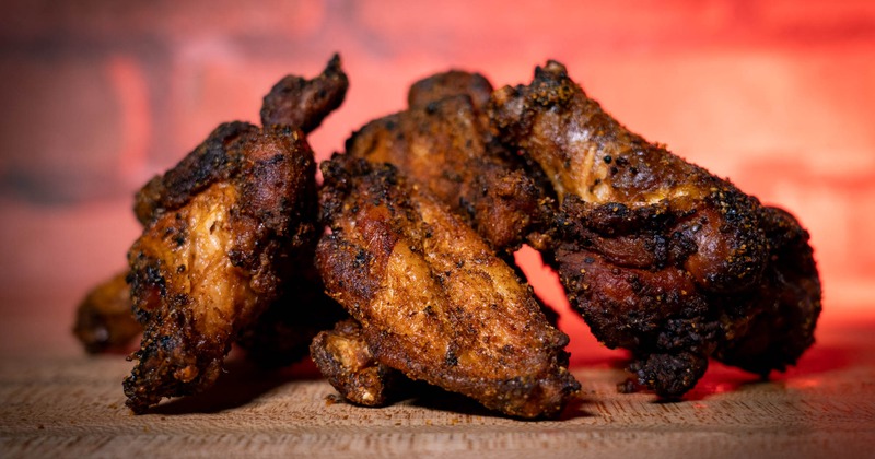 A serving of well-seasoned chicken wings on a wooden surface