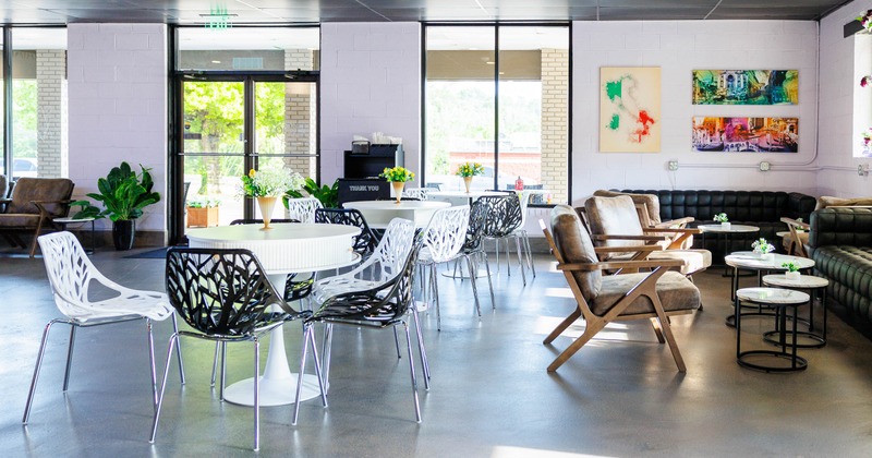 Modern cafe with white tables, black and white floral chairs, and cozy seating