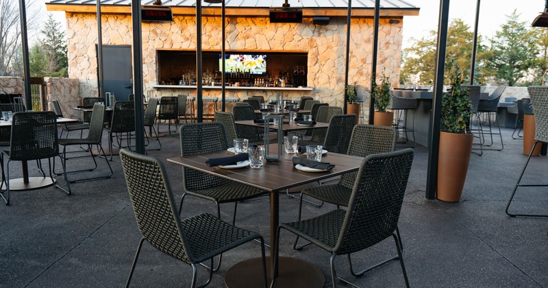 Outdoor patio with tables and chairs, a stone bar, and potted plants