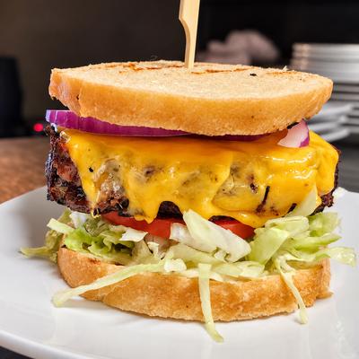 A cheeseburger with lettuce, tomato and red onion served between slices of toasted bread..