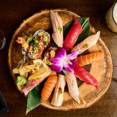 A platter featuring a variety of sushi and sashimi, presented on a wooden board.