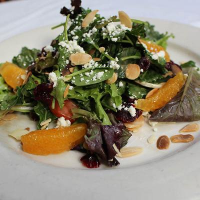 Mixed greens salad with orange slices, almonds, and cheese.
