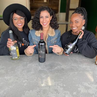 Interior, owners posing with news reporter and wine bottles.