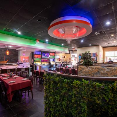 Interior, diner area, table, chairs, bar behind, green plant deco wall in front.
