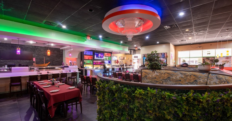 Interior, diner area, table, chairs, bar behind, green plant deco wall in front