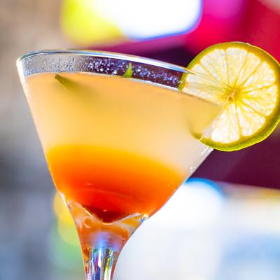 Citrus garnished cocktail in a stemmed glass.