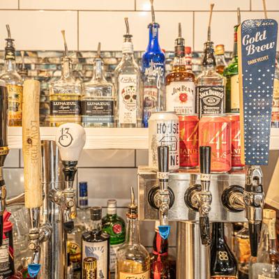 Bar area, beer taps, various liquor bottles lined up on the shelves, front view