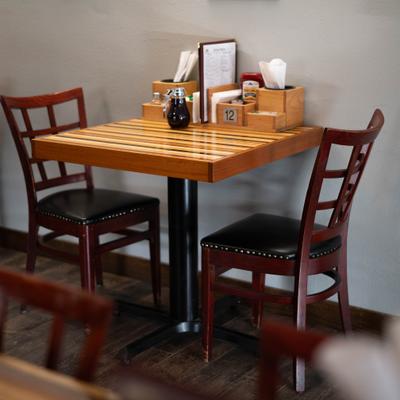 Multi-toned striped wooden table with two dark wood chairs.