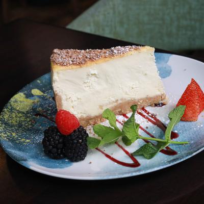 Cheesecake on a plate garnished with berries and mint.